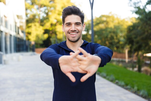 Confiant jeune sportif faisant des exercices d'étirement à l'extérieur