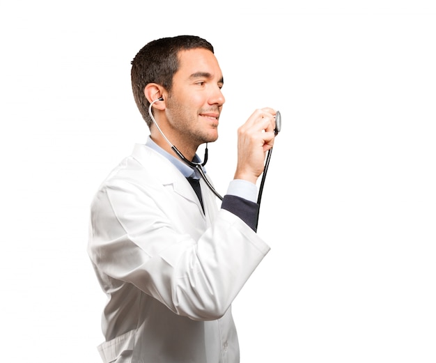 Confiant médecin utilisant un stéthoscope sur fond blanc