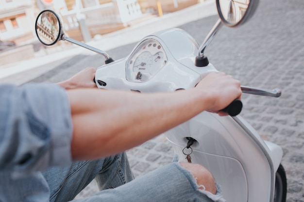 Confiant et séduisant jeune homme est assis sur une moto