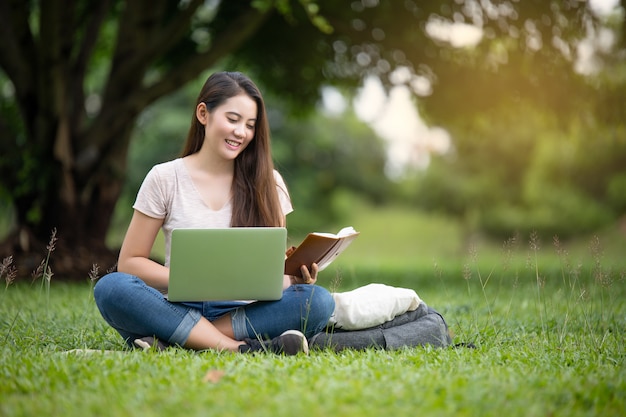Confiant souriante jolie jeune femme assise sur le lieu de travail en plein air avec ordinateur portable. Concept de travail