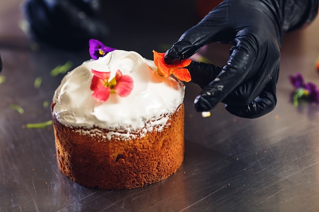 Confiseur décore le gâteau de Pâques avec des fleurs délicates.