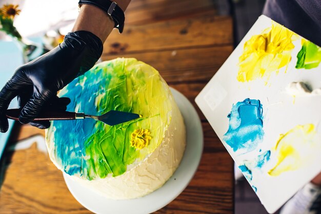 Photo confiseur décorer le gâteau avec de la crème colorée. gâteau à la main avec motif.