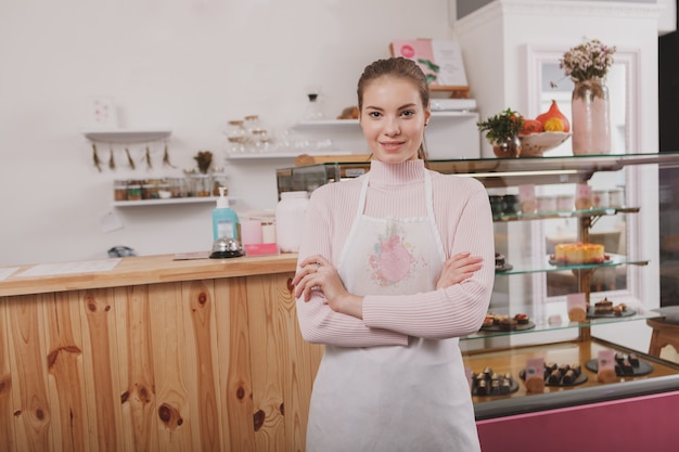 Confiseur femme posant fièrement dans son magasin de confiserie