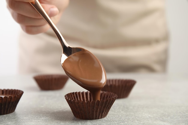 Confiseur professionnel faisant de délicieux bonbons au chocolat au gros plan de table gris