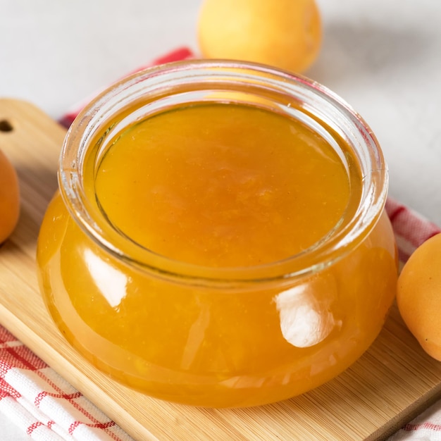 Confiture d'abricots dans un bocal en verre sur le plateau en bois Abricots frais Temps du petit-déjeuner Confiture de fruits au-dessus de la place