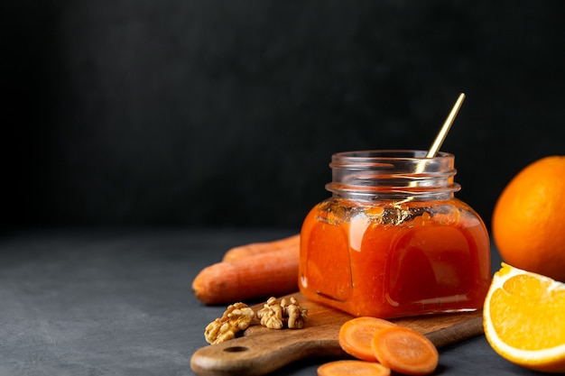 Confiture de carottes dans un pot avec une cuillère sur fond noir