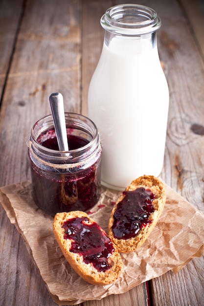 Confiture de cassis dans un bocal en verre, lait et craquelins