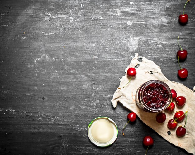 Confiture de cerises dans un pot sur l'ancien tissu.