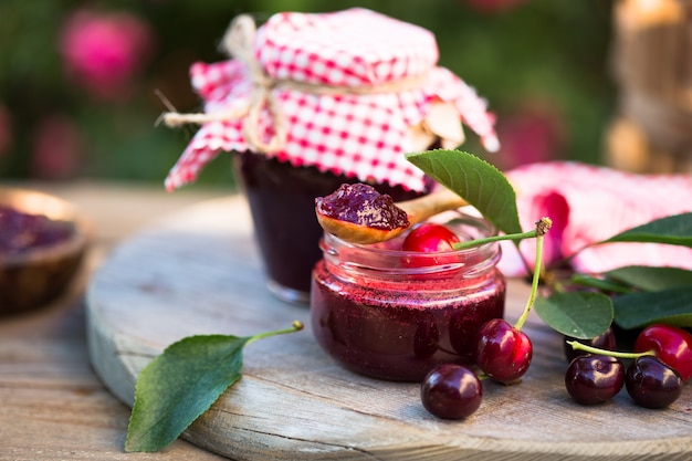 Confiture de cerises maison avec des cerises fraîches sur la table en bois