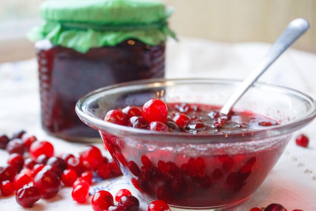 Confiture dans un bol, des baies et un pot de confiture sur une nappe blanche