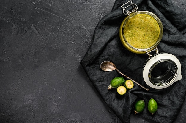 Confiture de feijoa verte sur une planche à découper en bois dans un bocal en verre.