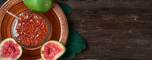 Confiture De Figues Dans Un Bocal En Verre Sur Un Plat Turc En Cuivre, Avec Des Moitiés De Figues Fraîches Et Une Feuille De Figuier à Côté