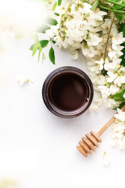 Confiture de fleurs d'acacia dans un bocal en verre sur fond blanc.