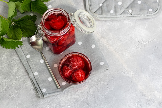 Confiture de fraises dans un bocal en verre à côté de fraises fraîches