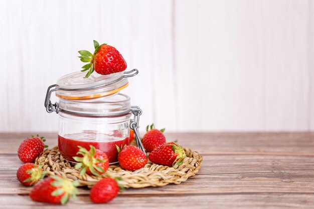 Confiture de fraises dans un pot sur fond de bois