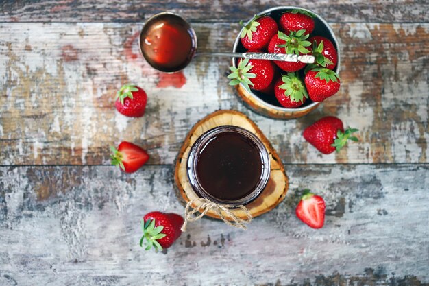 Confiture de fraises dans un pot et fraises fraîches.