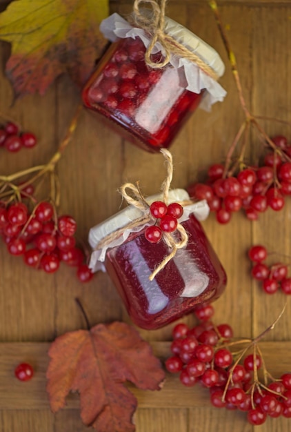 Confiture de fruits de viorne dans un bocal en verre sur une table en bois près des baies rouges mûres de viorne Source de vitamines naturelles Utilisé en médecine traditionnelle Récolte d'automne