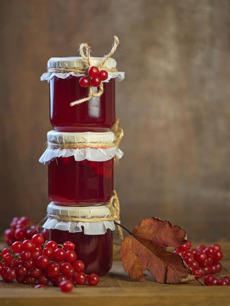 Confiture de fruits de viorne dans un bocal en verre sur une table en bois près des baies rouges mûres de viorne Source de vitamines naturelles Utilisé en médecine traditionnelle Récolte d'automne