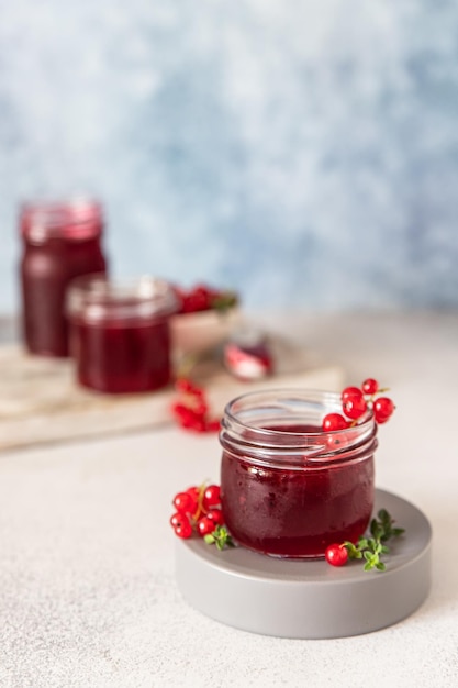 Confiture ou gelée de groseilles rouges maison dans des bocaux en verre et baies de groseilles rouges