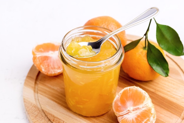 Confiture de mandarine d'agrumes savoureux dans un bocal en verre fond blanc au-dessus