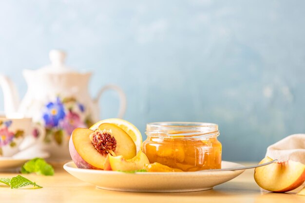 Confiture de pêches fraîches faites maison dans un bocal en verre sur un fond en bois