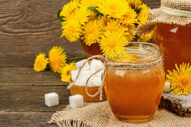 Confiture de pissenlit ou miel dans le bocal en verre avec un bouquet de fleurs de pissenlit en fleurs fraîches