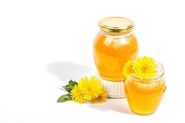 Confiture de pissenlit ou miel dans le bocal en verre avec des fleurs de pissenlit fraîches isolées sur fond blanc