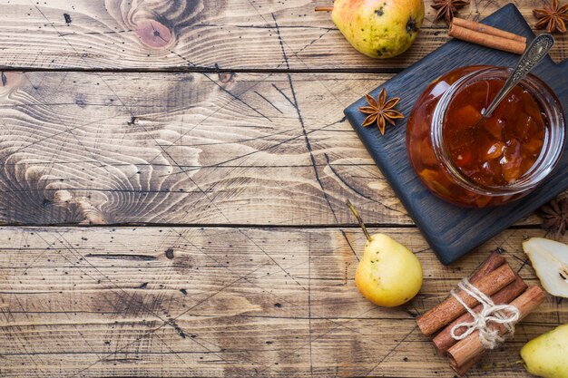 Confiture de poires faite maison dans un bocal et des poires fraîches sur un fond en bois