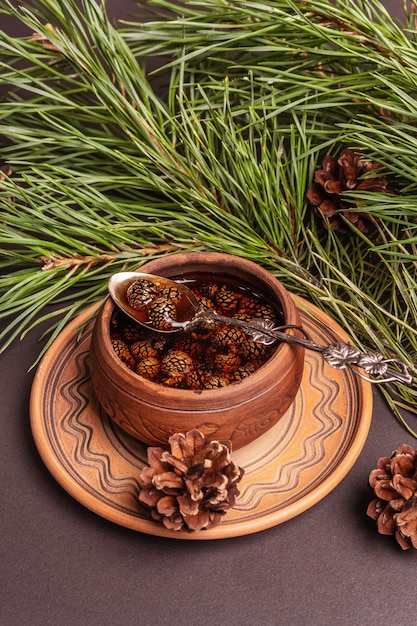 Confiture de pomme de pin sucrée. Dessert traditionnel sibérien, branches fraîches à feuilles persistantes. Fond de béton de pierre noire, gros plan