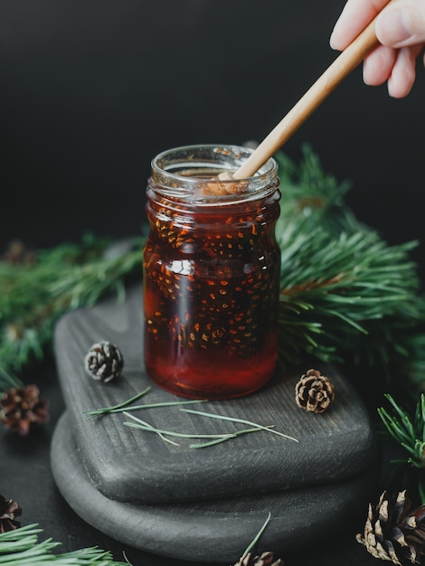 Confiture de pommes de pin dans un bocal en verre sur fond de branches et de pommes de pin