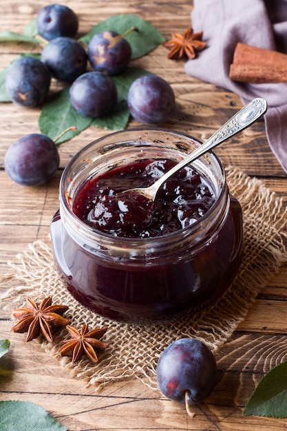 Confiture de prunes dans un bocal en verre. Fruit de prune fraîche sur une table en bois