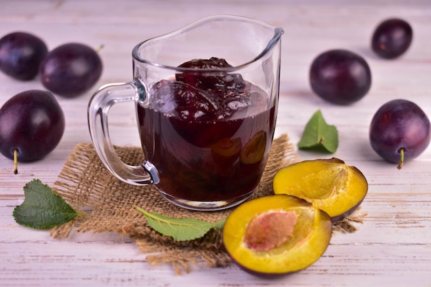 Confiture de prunes dans une saucière en verre sur un fond en bois de berme.