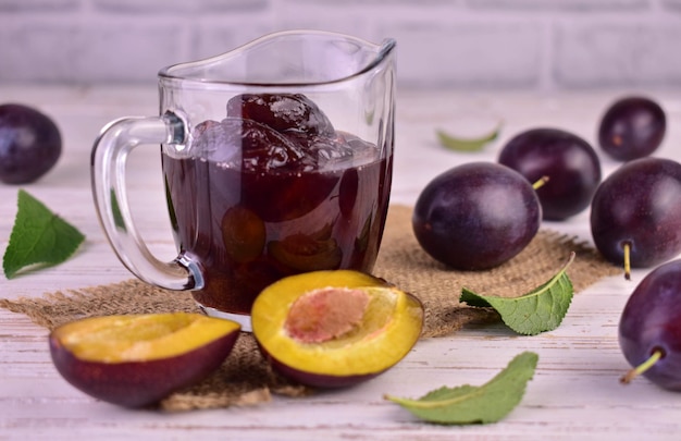 Confiture de prunes en saucière en verre. Sauce Tkemali. Fond blanc.