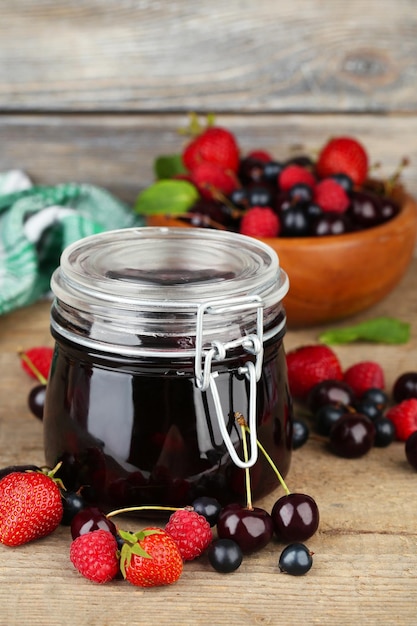 Confiture savoureuse avec des baies dans un bocal en verre sur une table en bois