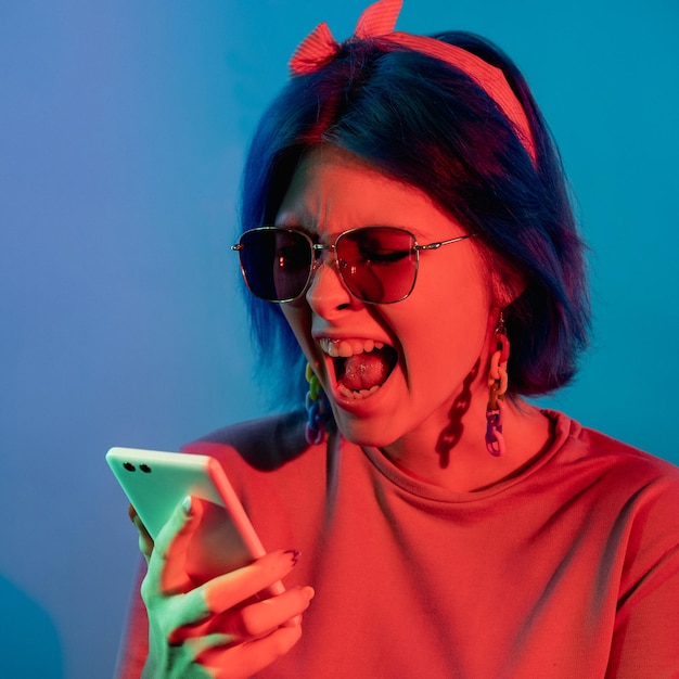 Conflit mobile Téléphone argumenter Problème de communication Femme en colère en néon rouge se plaignant d'une conversation sur smartphone isolée sur fond bleu