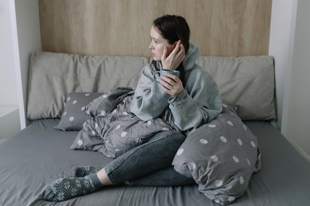 Confort du matin concept de maison confortable une jeune femme avec une tasse de café ou de cacao au lit à la maison