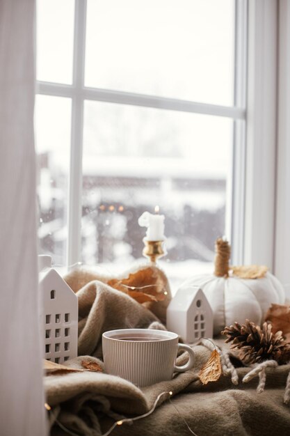 Photo confortable automne tasse de thé chaude oreillers de citrouille élégants feuilles d'automne bougies et décoration de bâtiments mignons sur une écharpe marron sur le rebord de la fenêtre automne hygge automne décoration de la maison