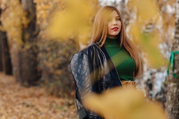 Confortable élégante jeune fille à pied au parc en automne