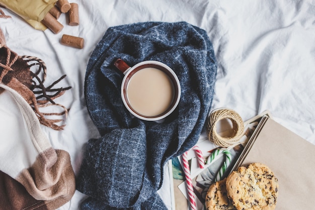 Confortable en hiver. Tasse avec café, biscuits, cadeau, branche de sapin, plaid sur le lit