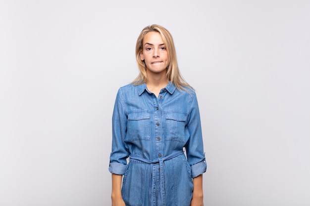 Confus jeune femme jolie blonde avec robe en jean