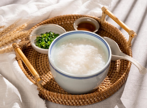 Congee pureday avec oignon de printemps dans un plat vue latérale sur fond gris