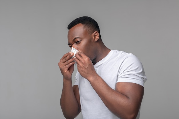 Congestion Nasale. Homme Afro-américain Triste En Tshirt Blanc Touchant Le Mouchoir Au Nez Se Sentant Malsain