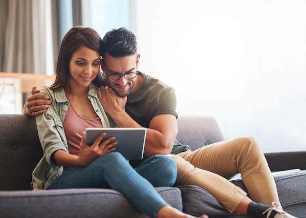 Connecté à un week-end confortable Photo d'un jeune couple utilisant une tablette numérique ensemble à la maison