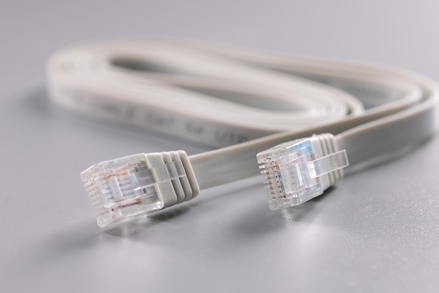 Connecteurs Internet blancs placés sur un câble à surface grise avec clip en plastique à l'extrémité