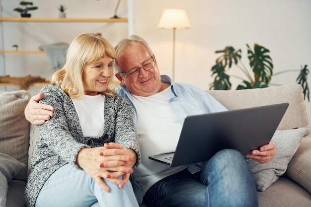 Connexion Internet À l'aide d'un ordinateur portable Un homme et une femme âgés sont ensemble à la maison