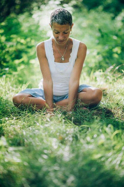 Photo connexion avec la nature une femme consciente assise sur le sol entourée d'une nature magnifique