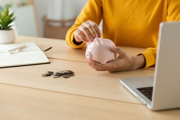 Économiser de l'argent en investissement pour l'avenir Mains de femme tenant une tirelire rose et mettre une pièce d'argent Économie d'investissement budget entreprise richesse retraite argent financier concept bancaire