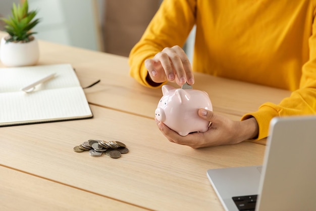 Économiser de l'argent en investissement pour l'avenir Mains de femme tenant une tirelire rose et mettre une pièce d'argent Économie d'investissement budget entreprise richesse retraite argent financier concept bancaire