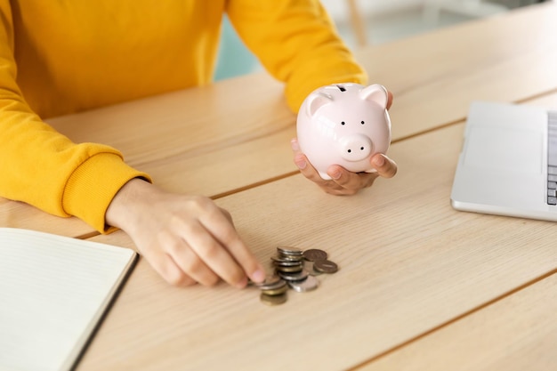 Économiser de l'argent pour les futures mains de femmes tenant une tirelire rose et mettant une pièce d'argent