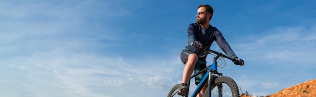 Conquérir les sommets des montagnes par un cycliste en short et en maillot sur un vélo semi-rigide moderne en carbone avec une fourche à suspension pneumatique